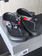 Pair of black platform sandals with perforated detailing, bows, and heart accents