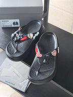 Black platform sandals with bow ties and heart-shaped patches on the straps