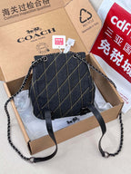 Coah bag dark denim bucket crossbody with chain and leather strap, flap front