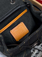 Coah bag denim interior pocket with tan leather logo patch and black strap