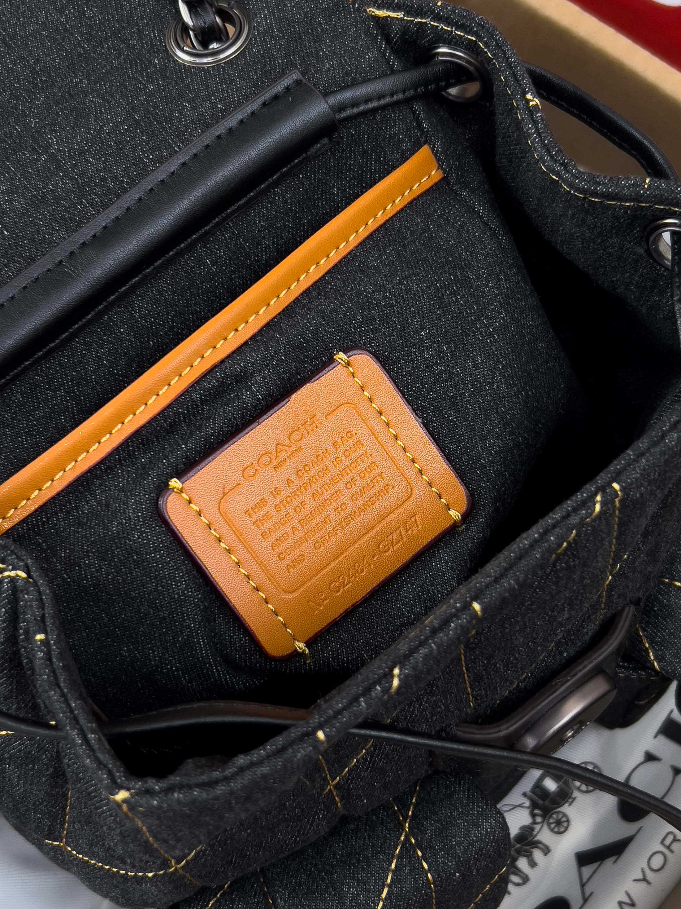Coah bag denim interior pocket with tan leather logo patch and black strap