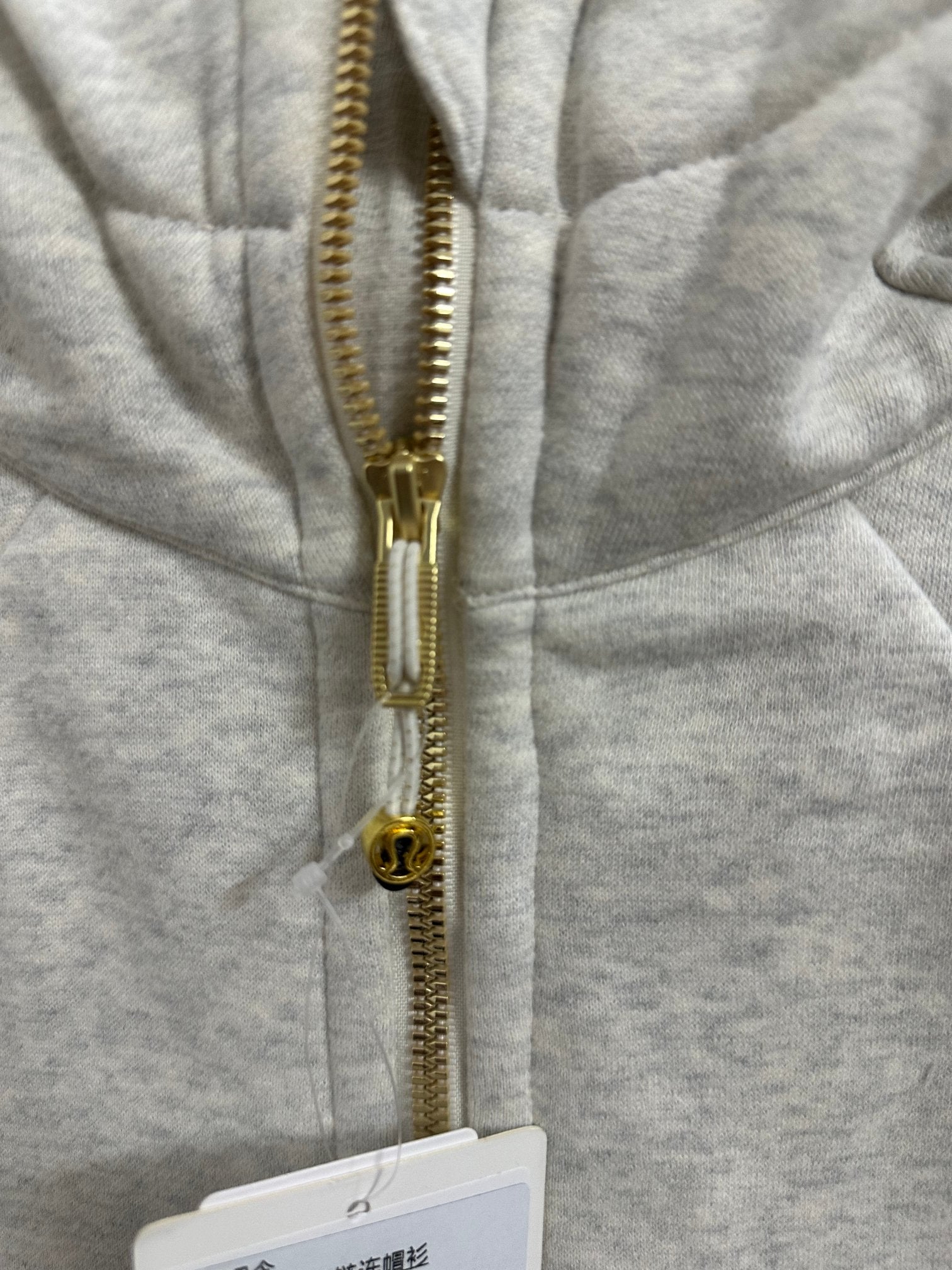 Light gray hoodie zipper with gold pull and teeth
