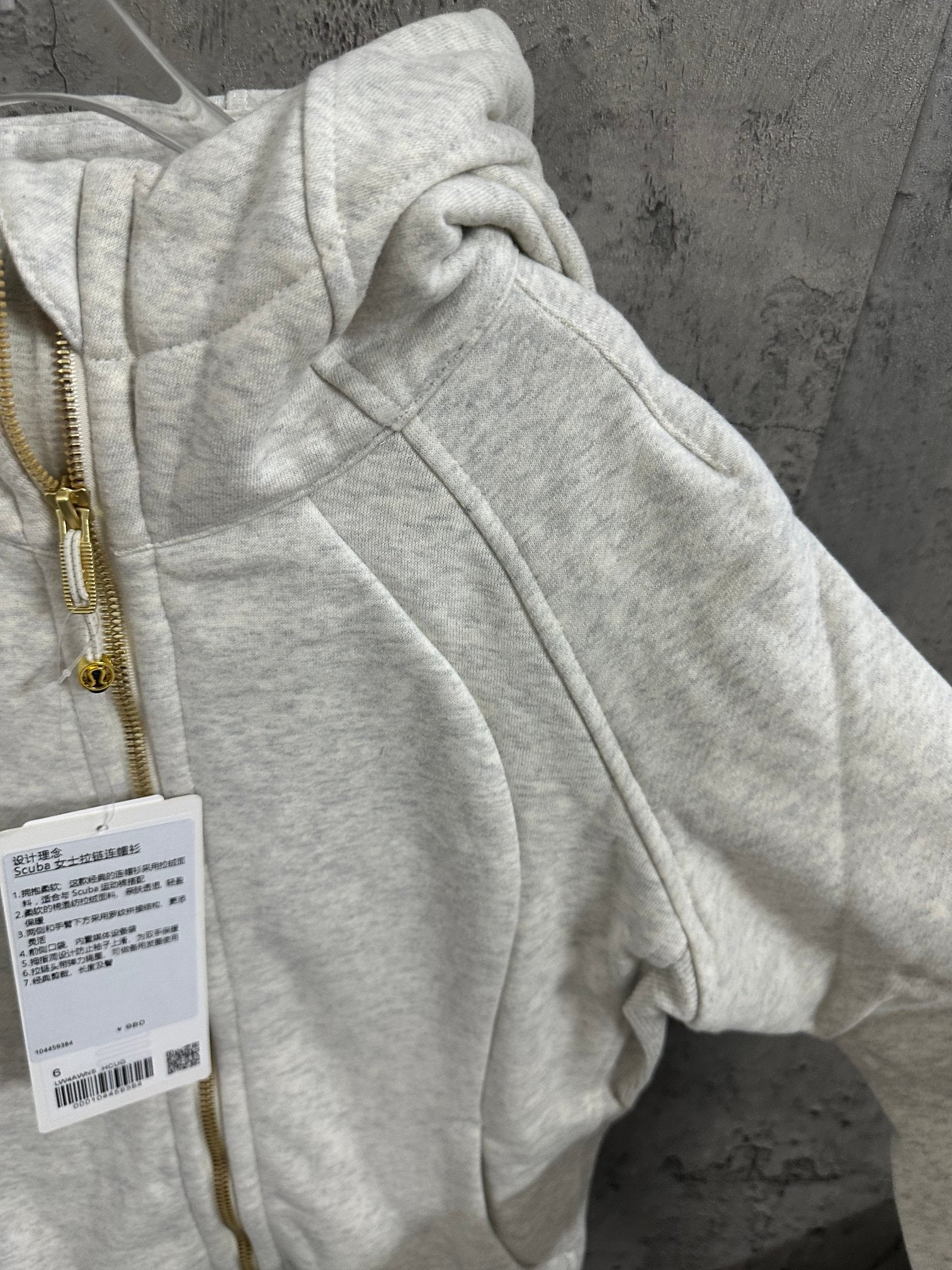 Light gray zip-up hoodie with draped hood and gold zipper track