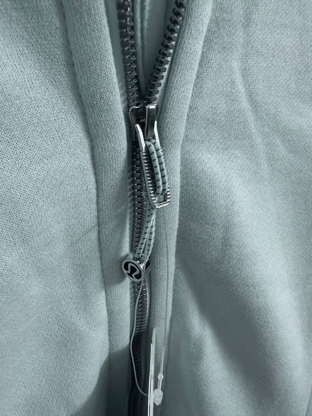 Close-up of a light blue hoodie zipper with metal pull tab