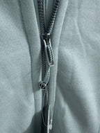 Close-up of a light blue hoodie zipper with metal pull tab