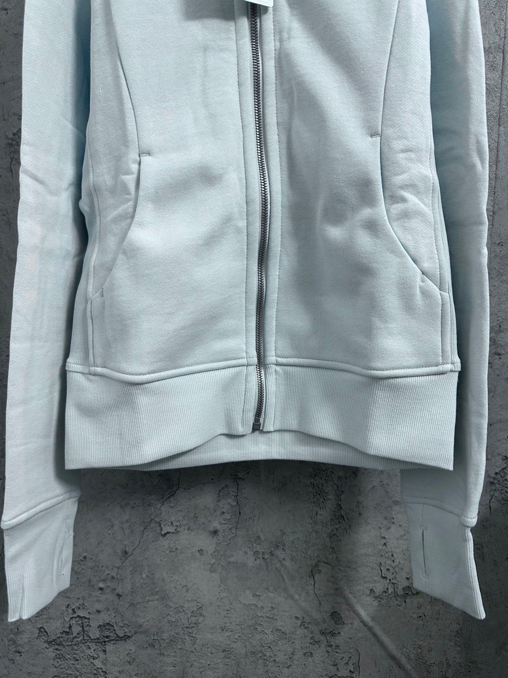 Light blue zip-up hoodie front with central zipper and side pocket seams