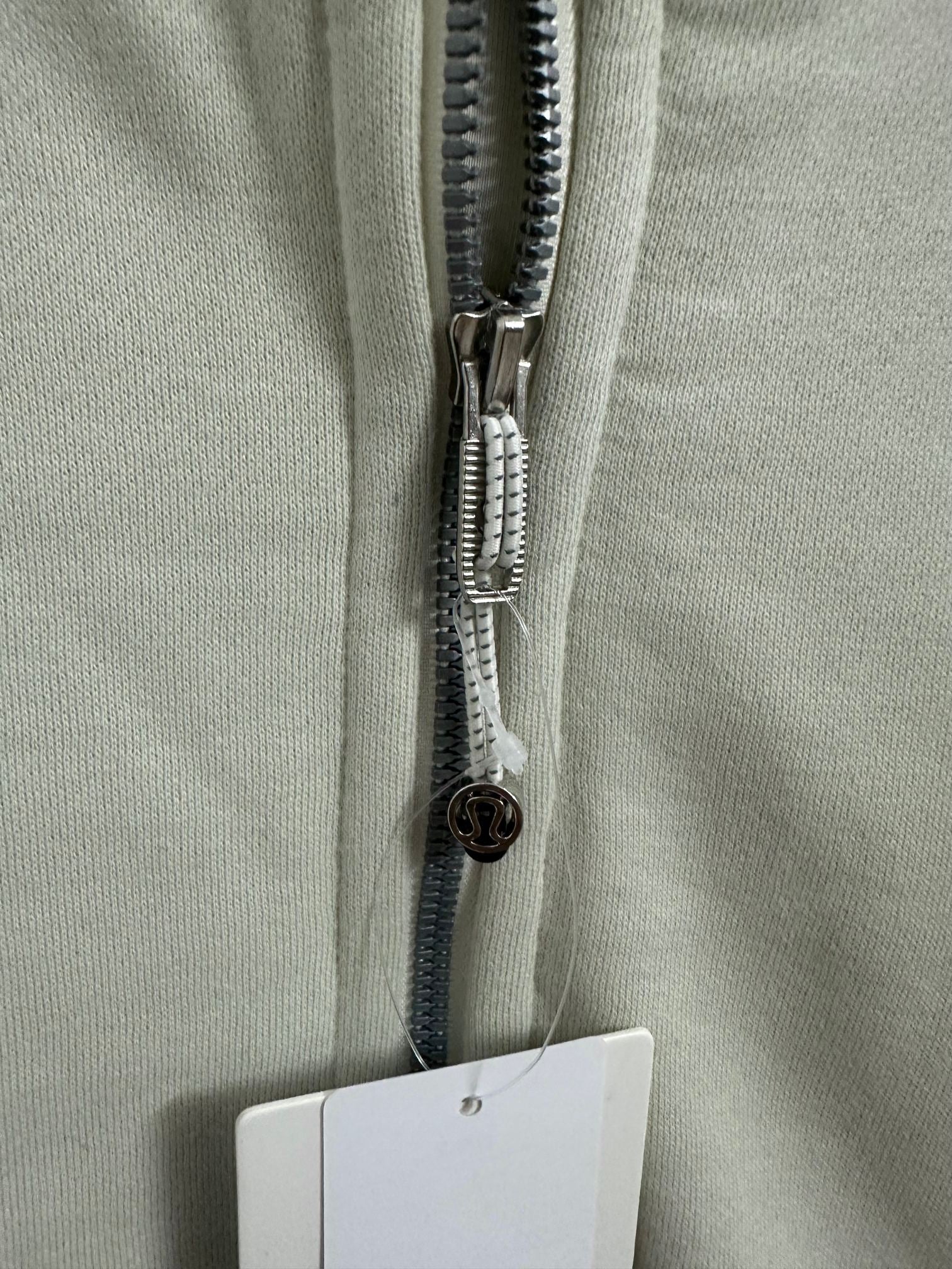 Off-white hoodie zipper close-up with pull tab and inner label