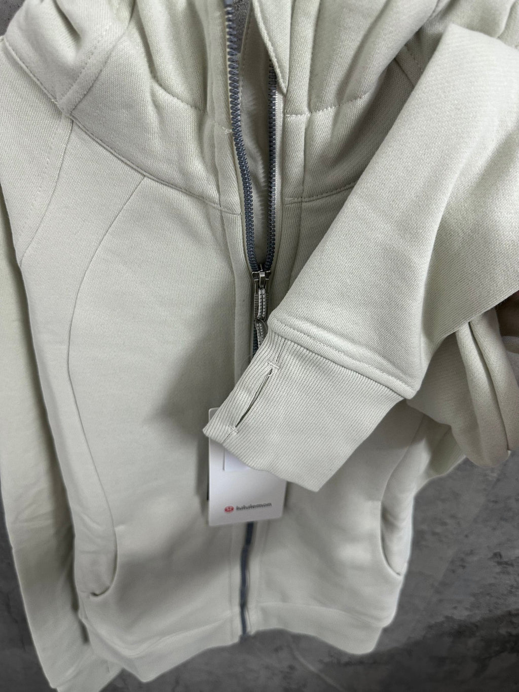 Off-white zip-up hoodie front with zipper and ribbed sleeve cuff
