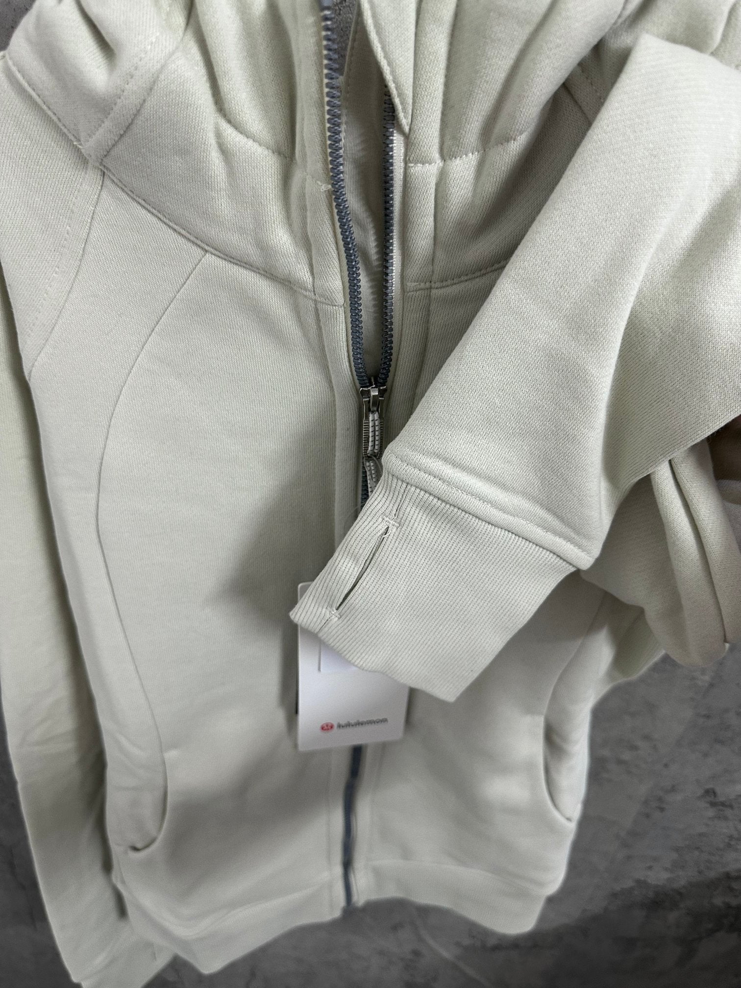 Off-white zip-up hoodie front with zipper and ribbed sleeve cuff