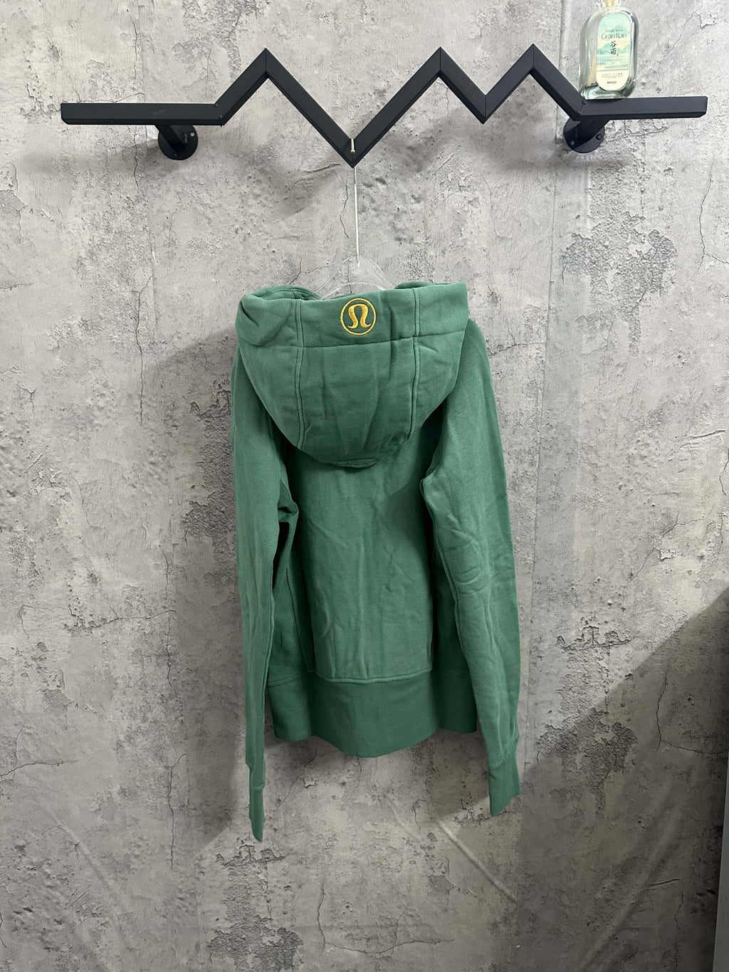 Green hooded zip hoodie with small yellow crest on the hood