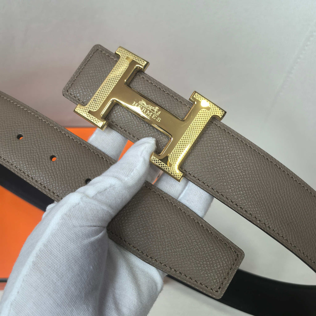 Taupe leather belt with gold H buckle and punched sizing holes on the strap