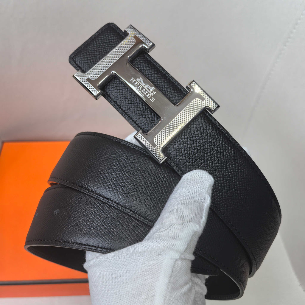 Black leather belt with silver rectangular Hermes buckle, textured strap