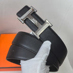 Black leather belt with silver rectangular Hermes buckle, textured strap