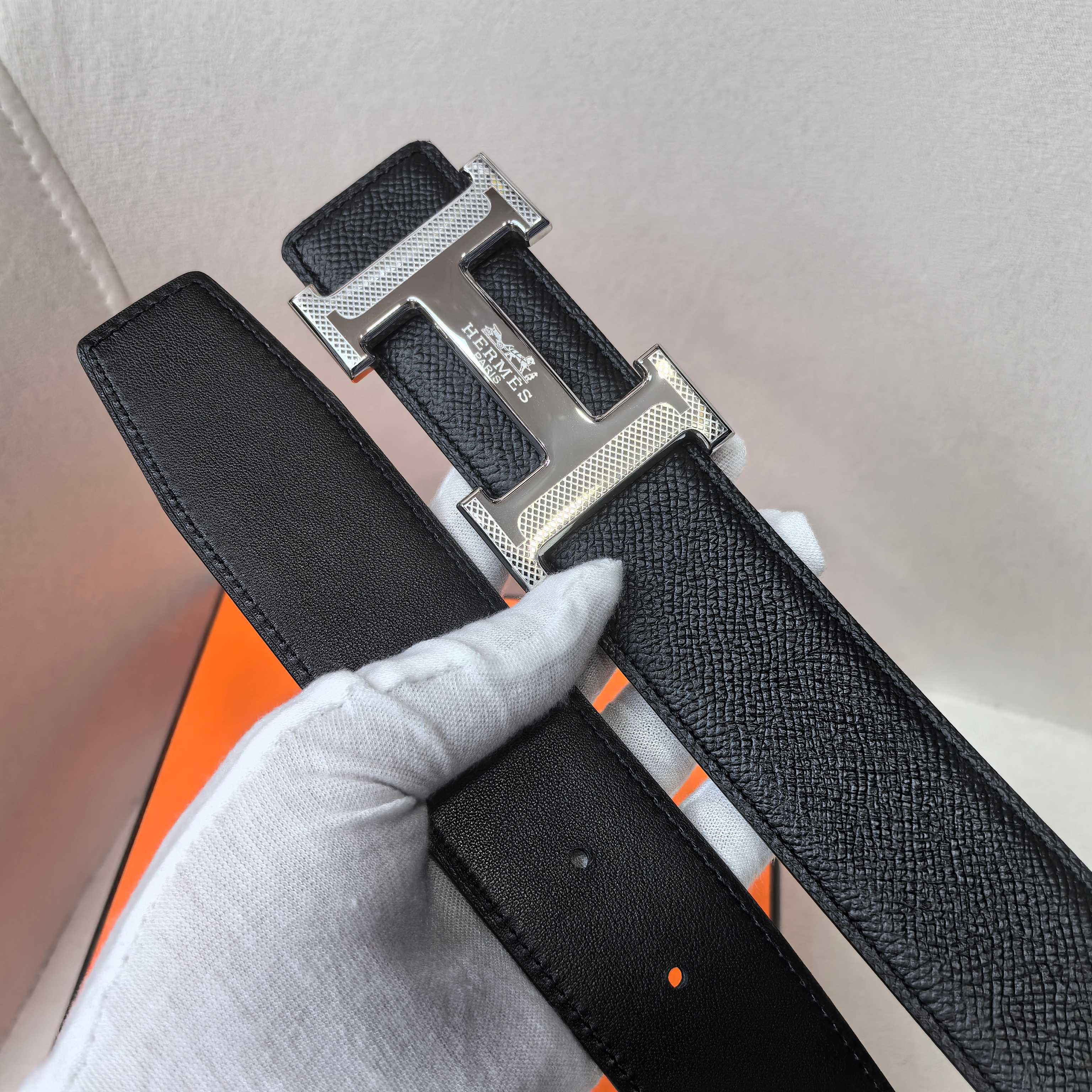 Black leather belt close-up of textured strap and silver buckle hardware