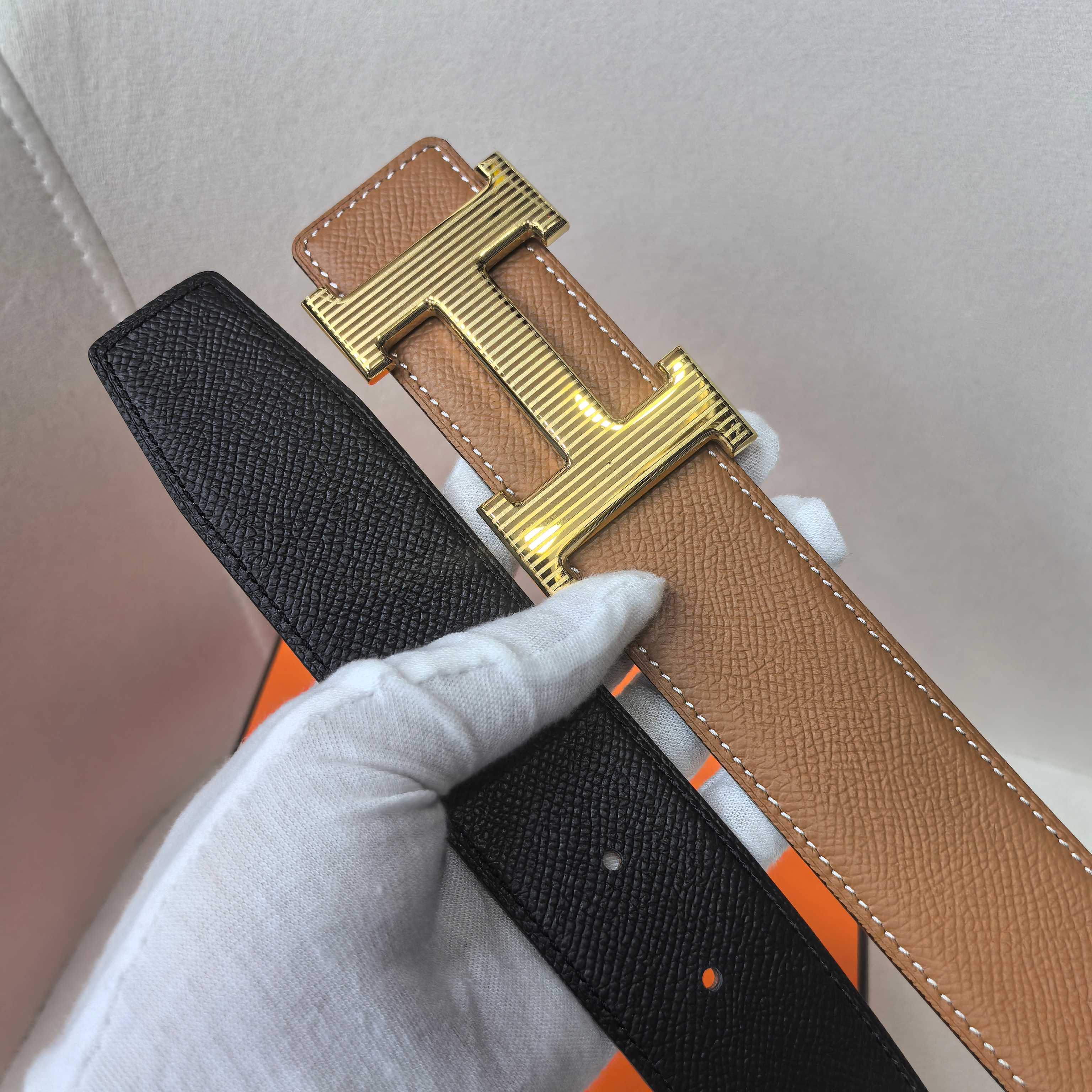 Leather belt with tan strap and black underside, gold H buckle