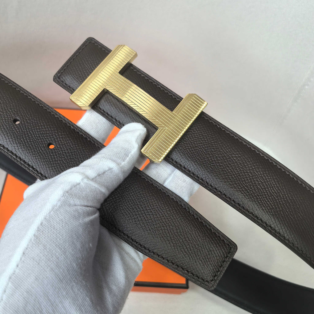 Black leather belt detail: gold-tone H buckle and inner keeper strap.