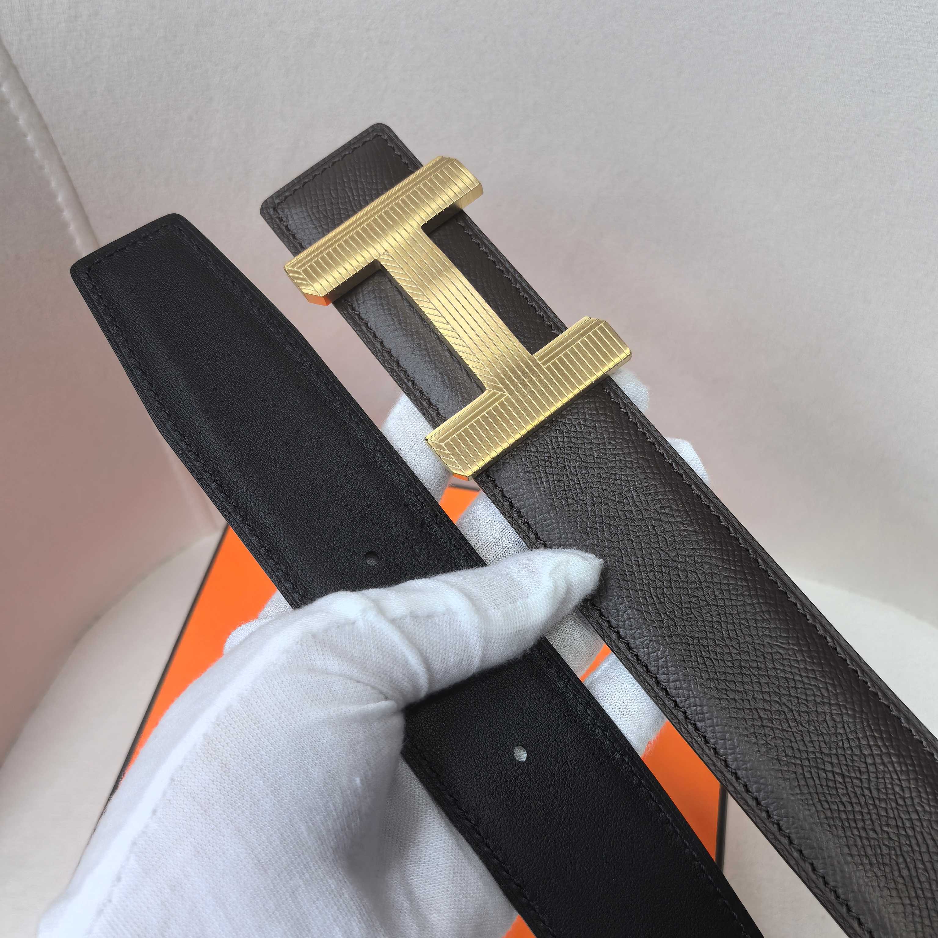 Black leather belt with gold-tone H buckle and separate inner strap keeper.
