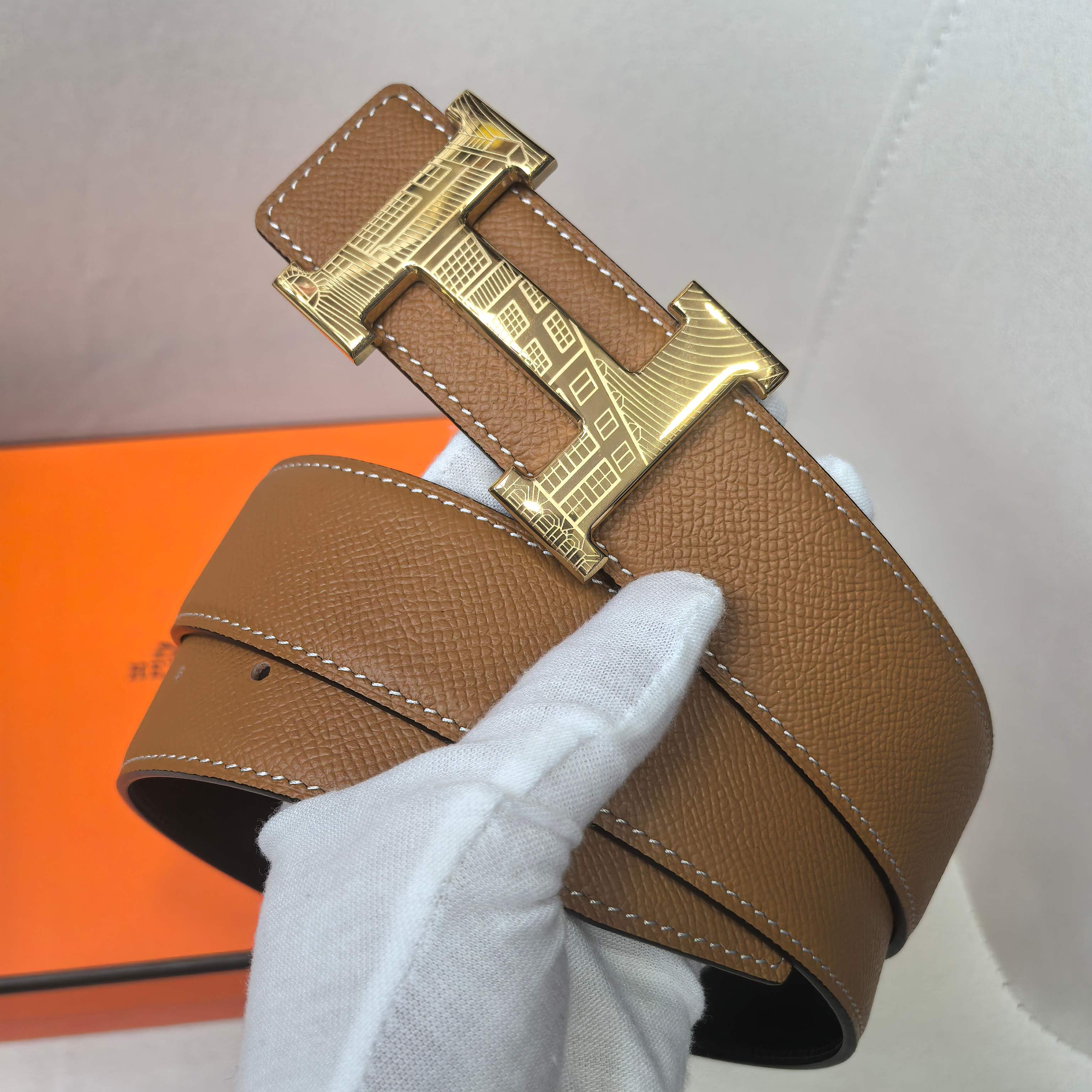 Brown leather belt with gold geometric buckle and stitched edge