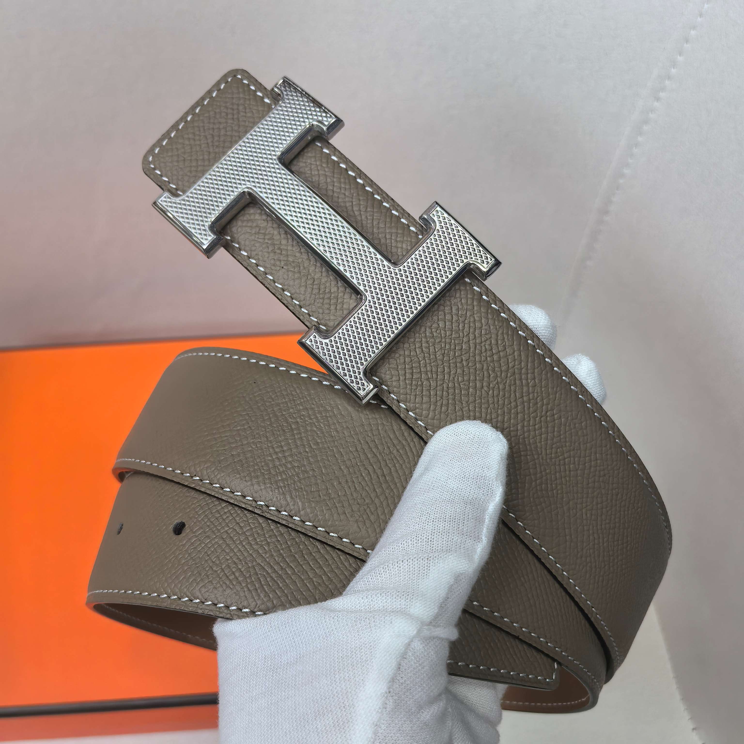 Brown leather belt with silver H buckle and contrast-stitched edges