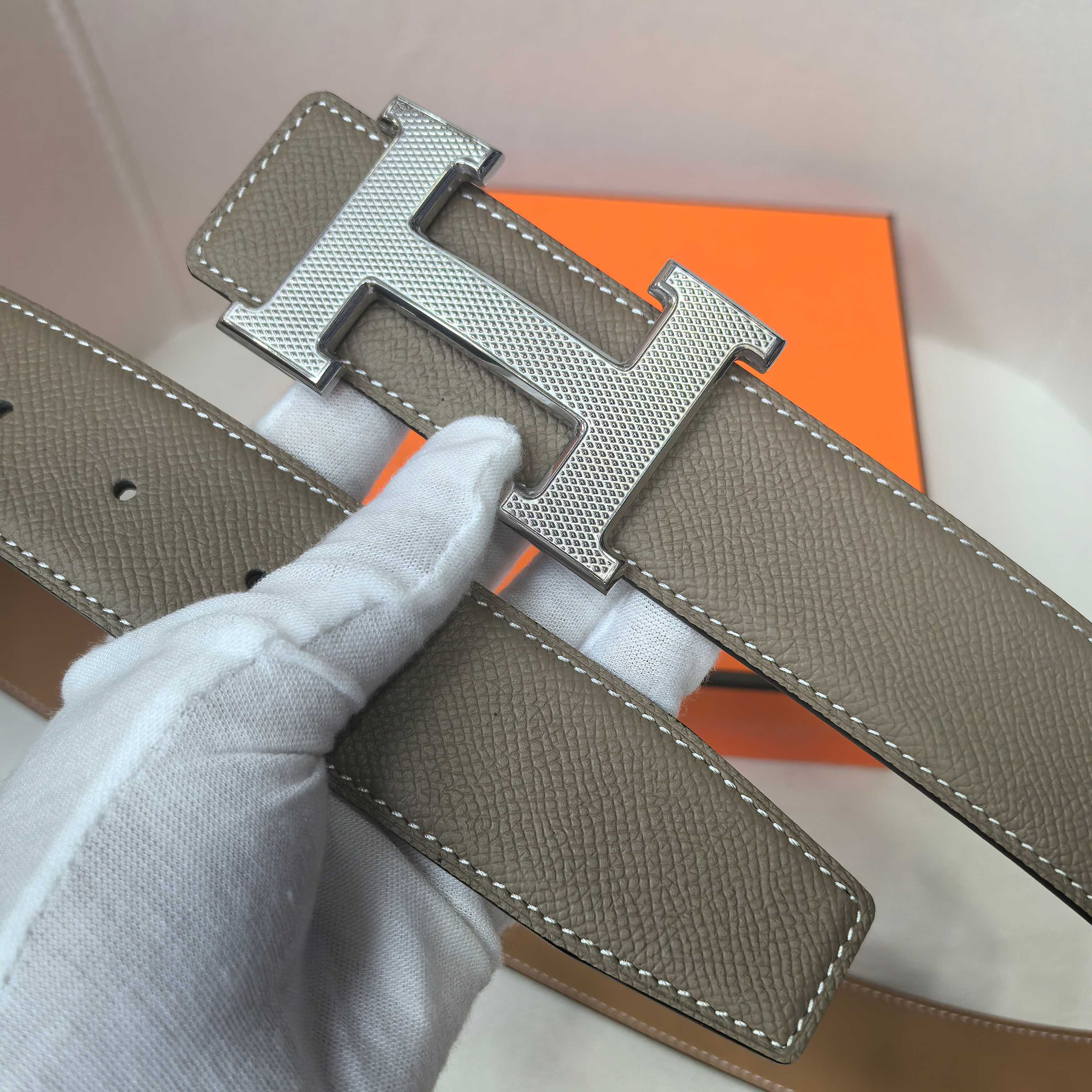 Brown leather belt with silver H buckle and textured strap end