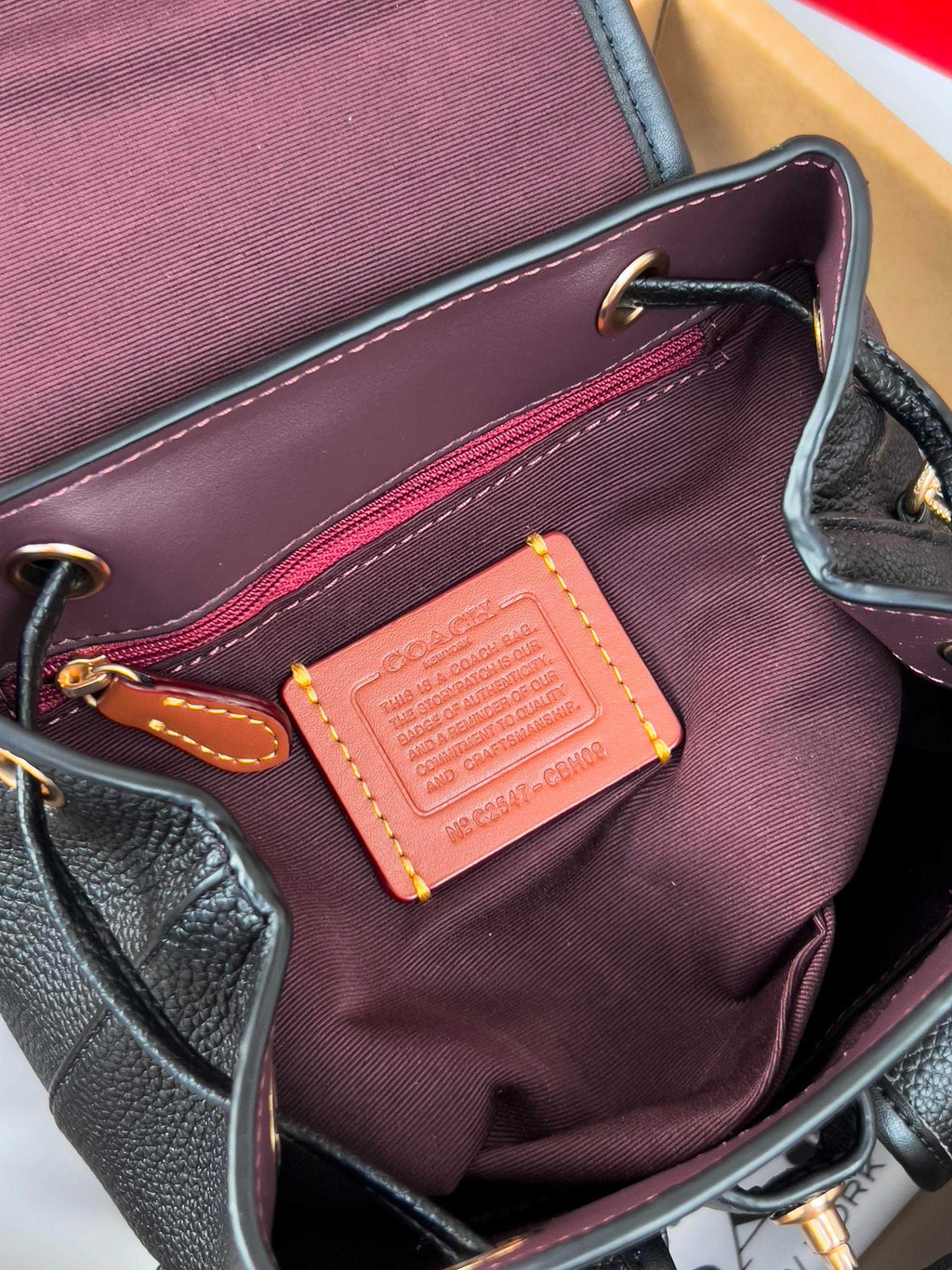 Coah mini backpack interior with burgundy lining, leather trim, and rectangular tag patch