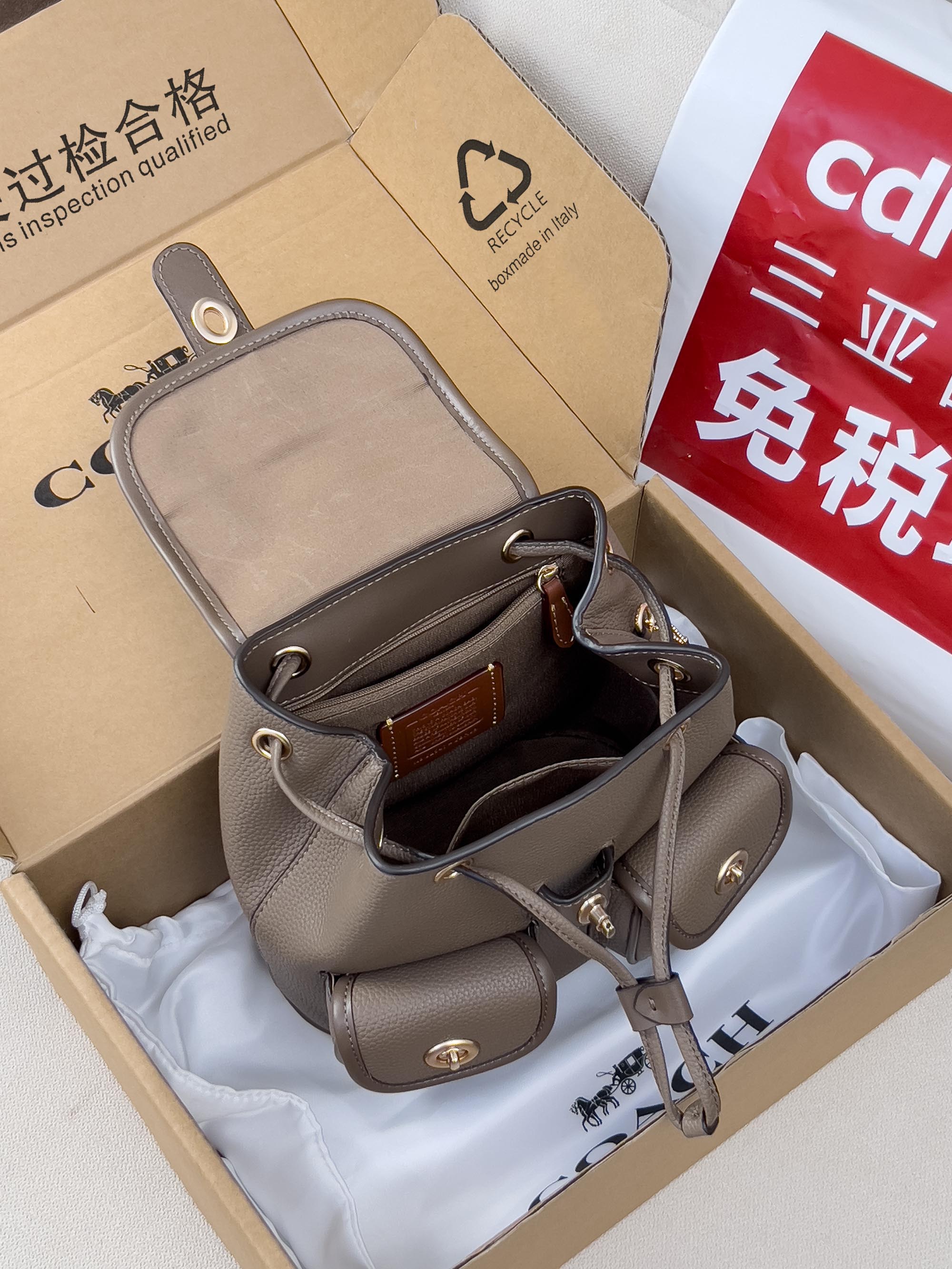 Coach mini backpack bag in taupe with open top, interior pockets, and shoulder straps
