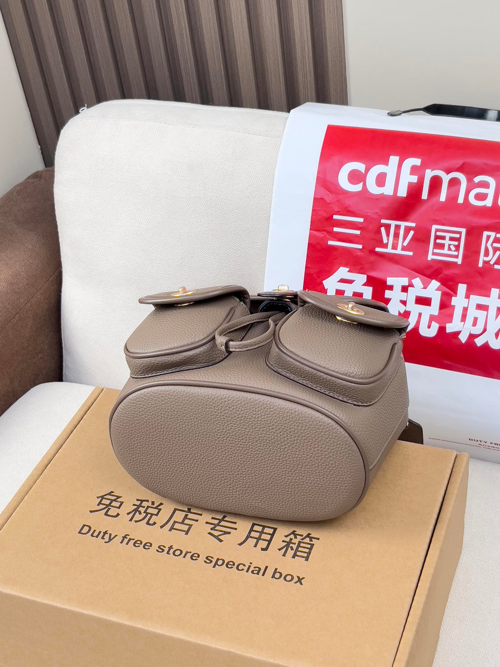 Coach mini backpack bag in taupe on a duty-free store box, rounded top flap