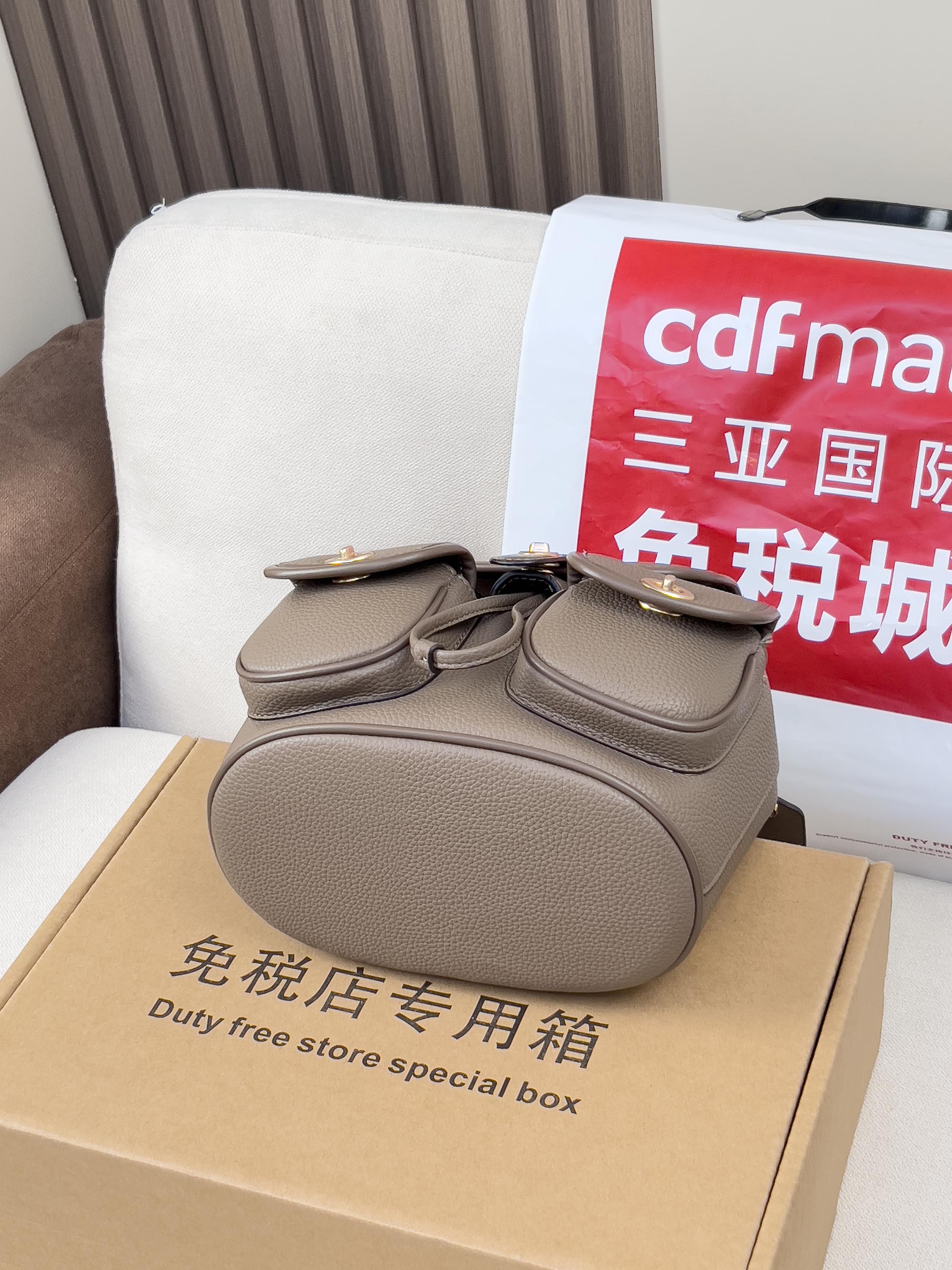 Coach mini backpack bag in taupe on a duty-free store box, rounded top flap