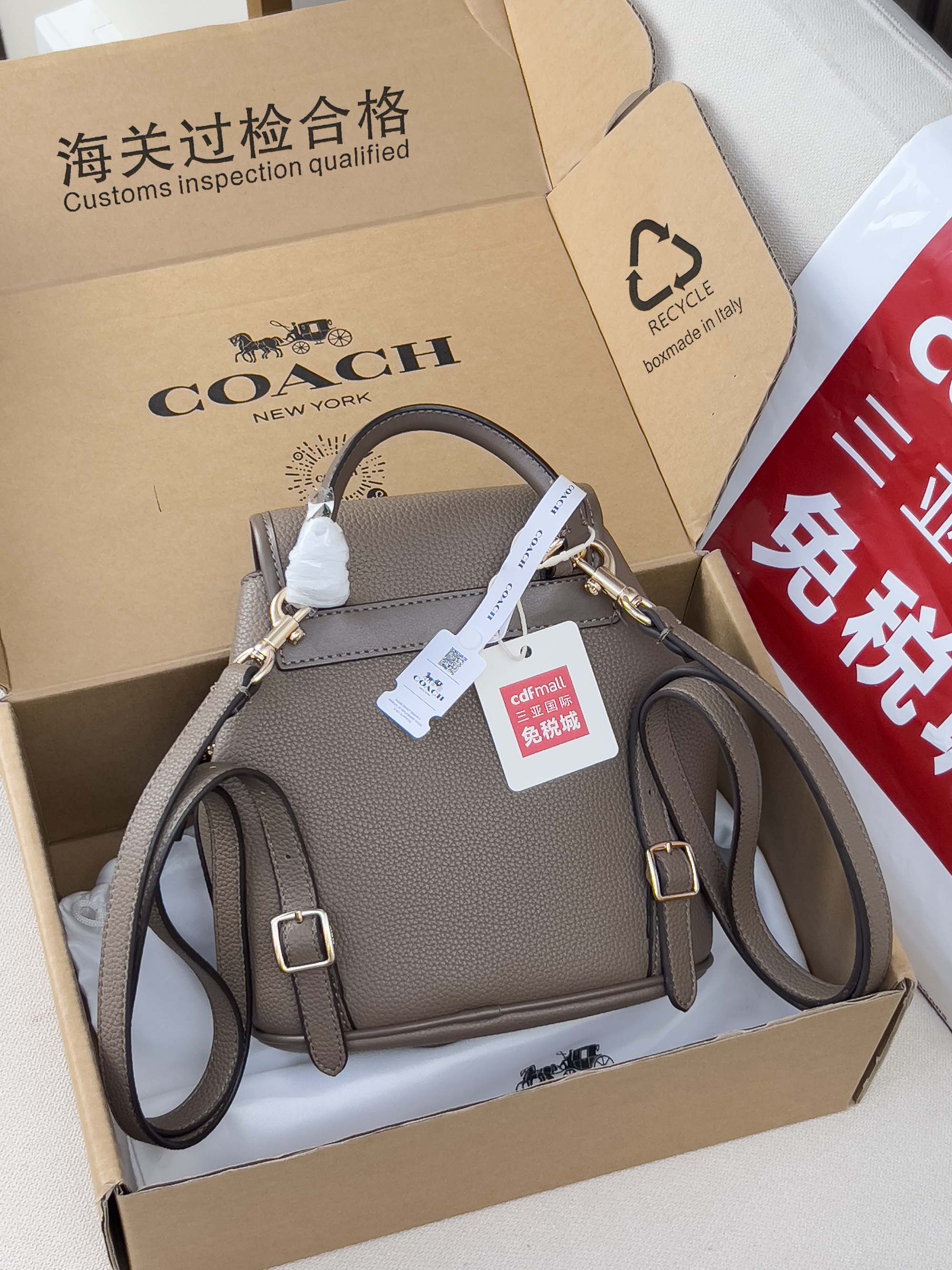 Coach mini backpack bag in taupe with flap, dual straps, and side pocket details