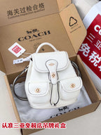 White mini backpack bag with flap front, top handle, and drawstring tie