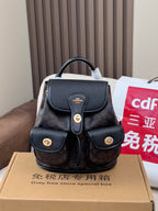 Coah mini backpack with black top flap and dual front pockets, gold button details
