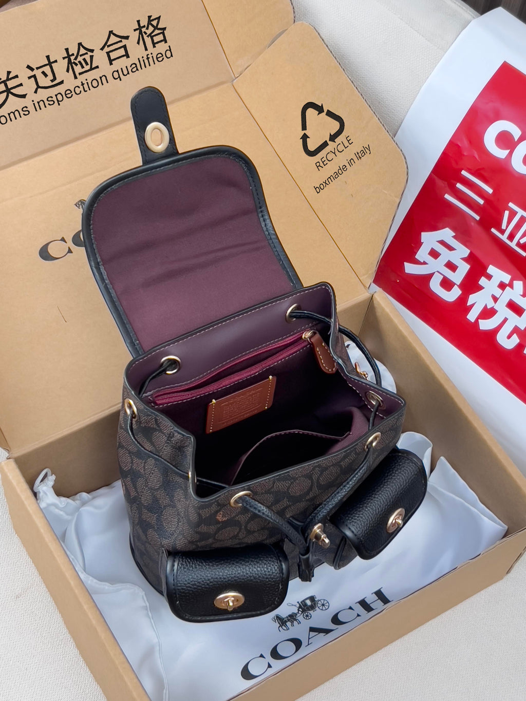 Coah mini backpack with dark patterned exterior, open top, and burgundy-lined interior pockets
