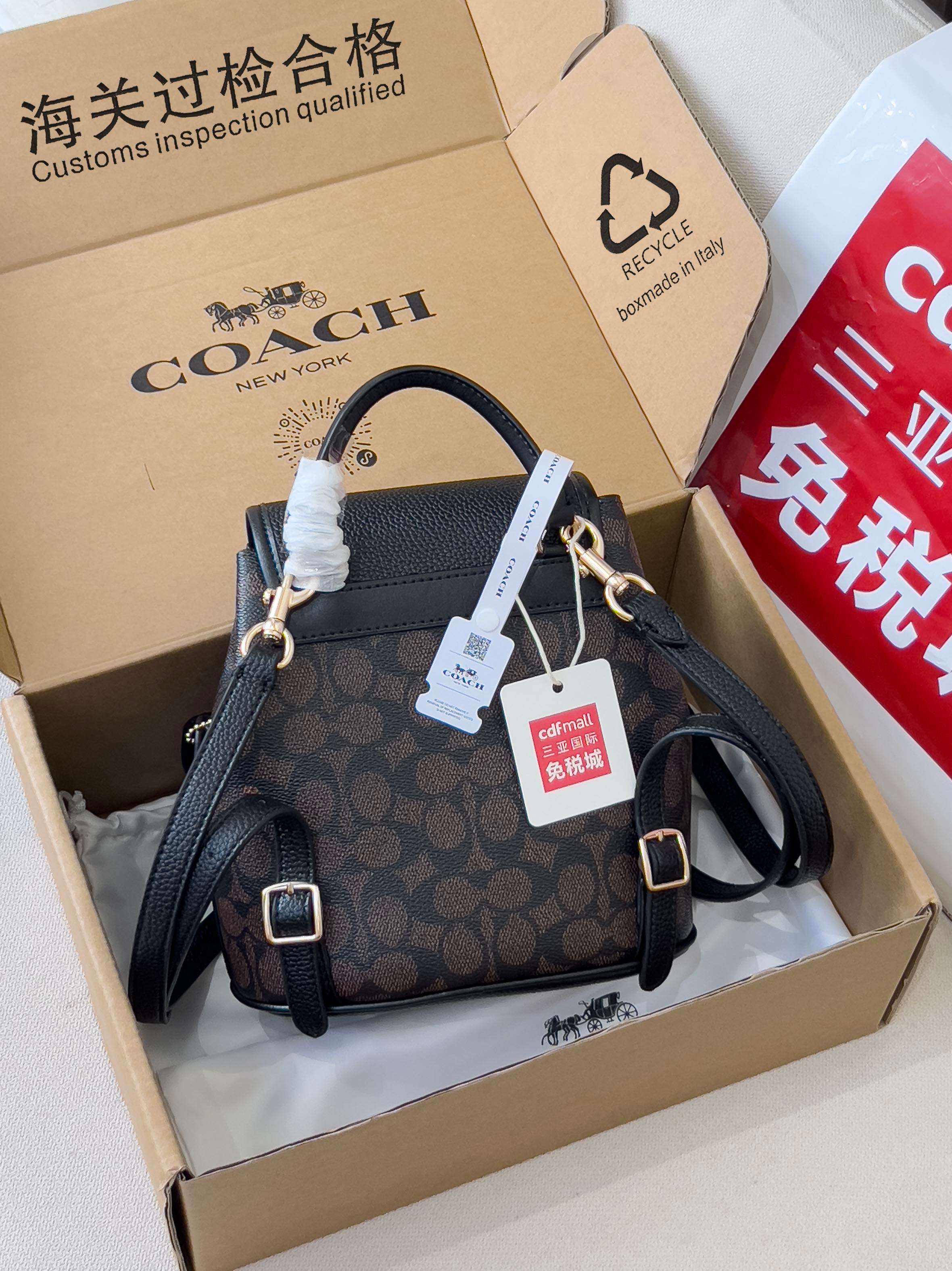 Coah mini backpack with dark logo fabric, top handle, side straps, and gold buckles
