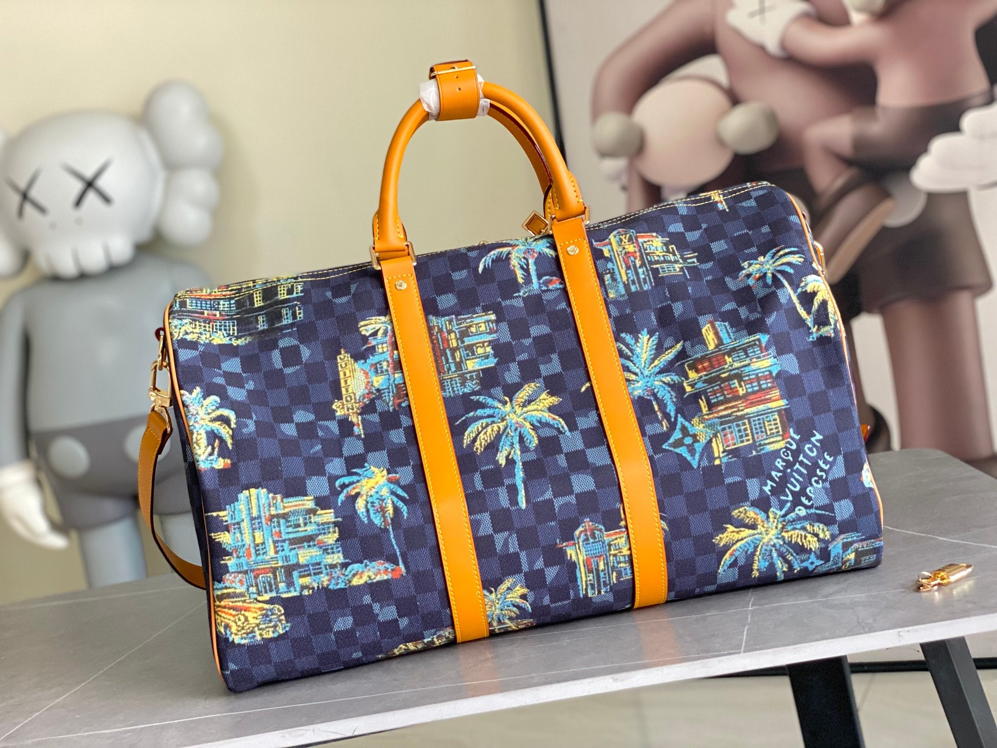 Louis Vuitton handbag, navy check canvas with colorful city-and-palm print, orange leather straps.