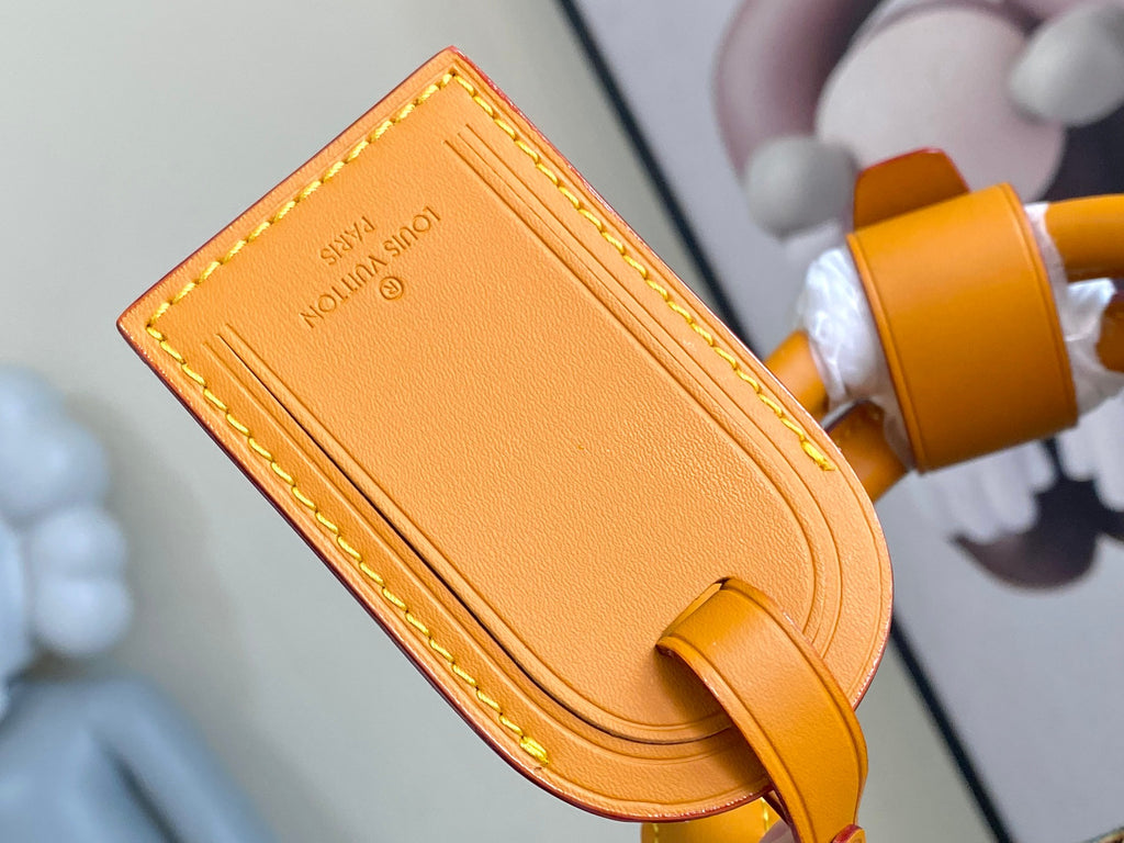 Orange leather tab with embossed “LOUIS VUITTON PARIS” lettering and curved edge.