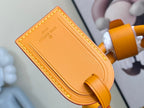 Orange leather tab with embossed “LOUIS VUITTON PARIS” lettering and curved edge.