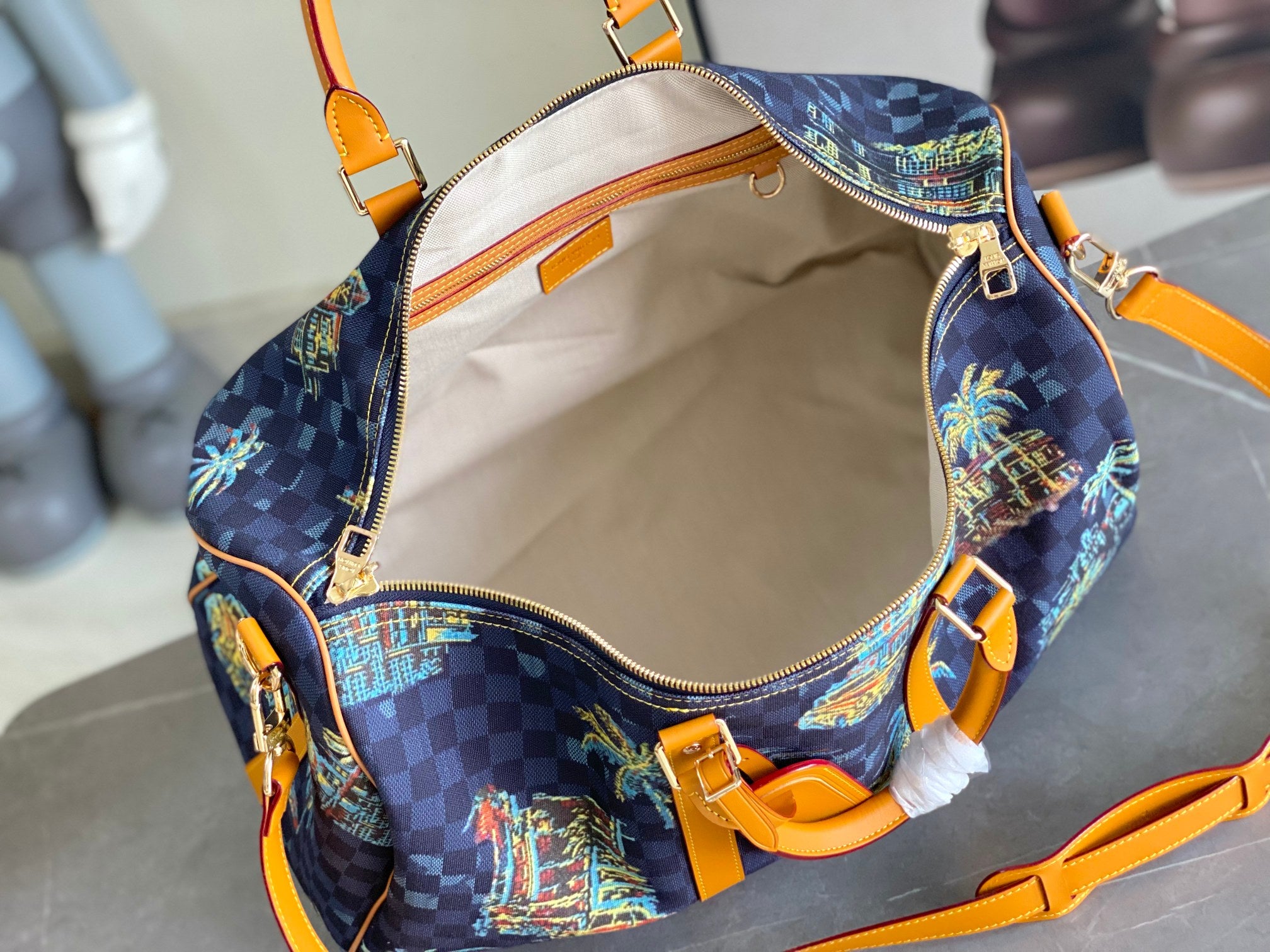 Open Louis Vuitton handbag showing cream fabric lining, top zipper, and orange strap hardware.