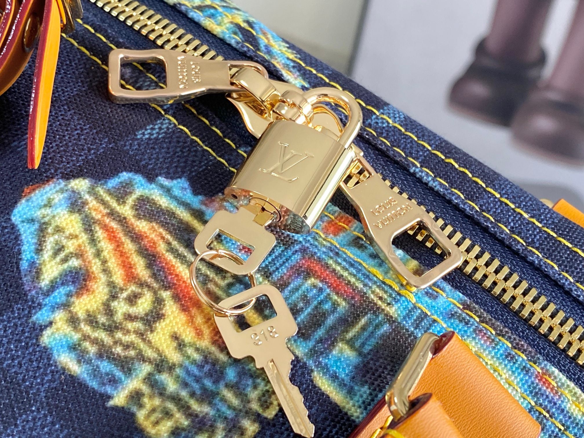 Gold zipper hardware on navy printed canvas with orange edging and colorful motif detail.