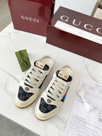 Gucci low-top sneakers with white laces, navy GG canvas, and multicolor stripe detail