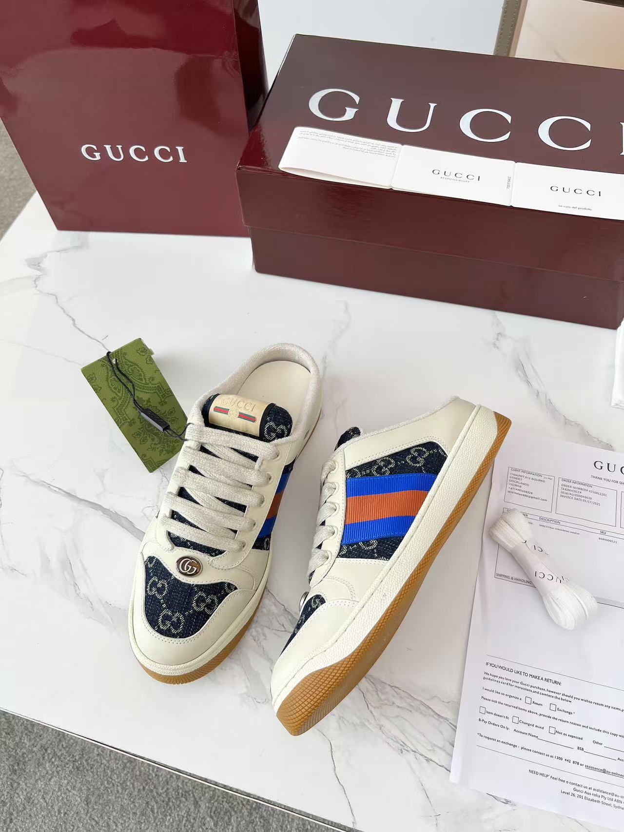 Gucci low-top sneakers with white laces, navy GG canvas toe, and multicolor side stripe