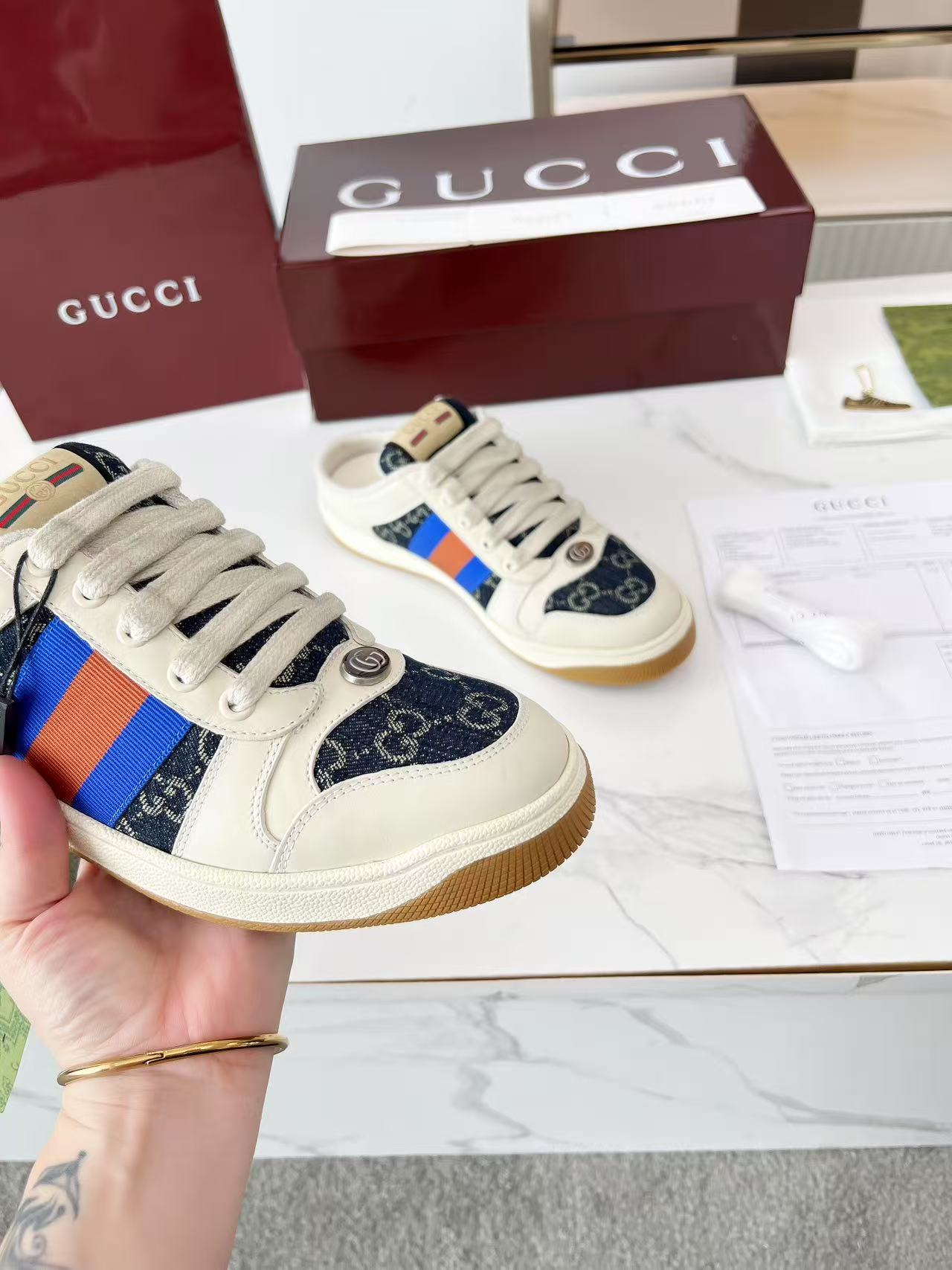 Gucci low-top sneakers pair, navy GG canvas with multicolor stripe and tan rubber sole