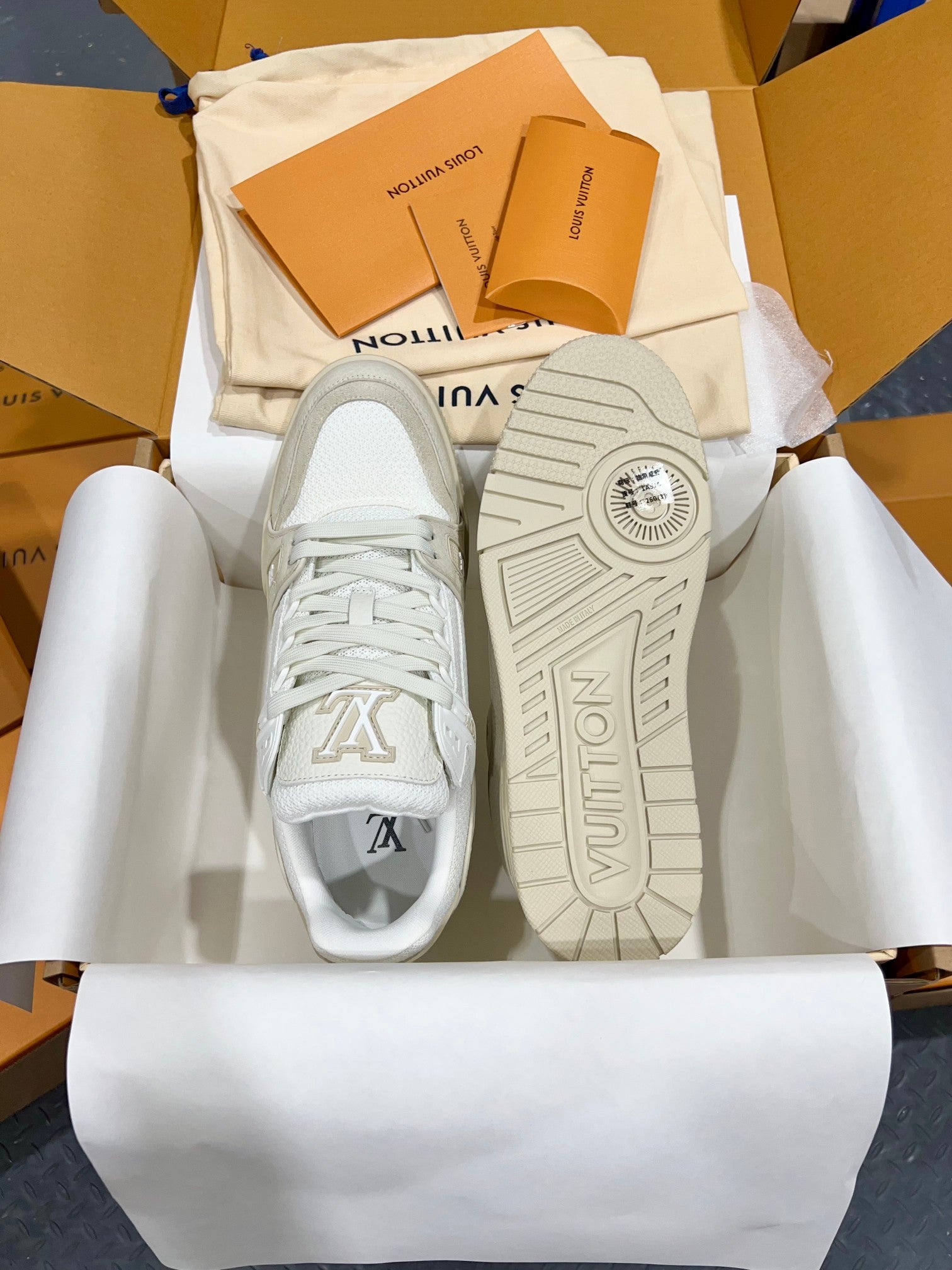 White Louis Vuitton trainer shoes with treaded rubber outsoles shown from bottom.