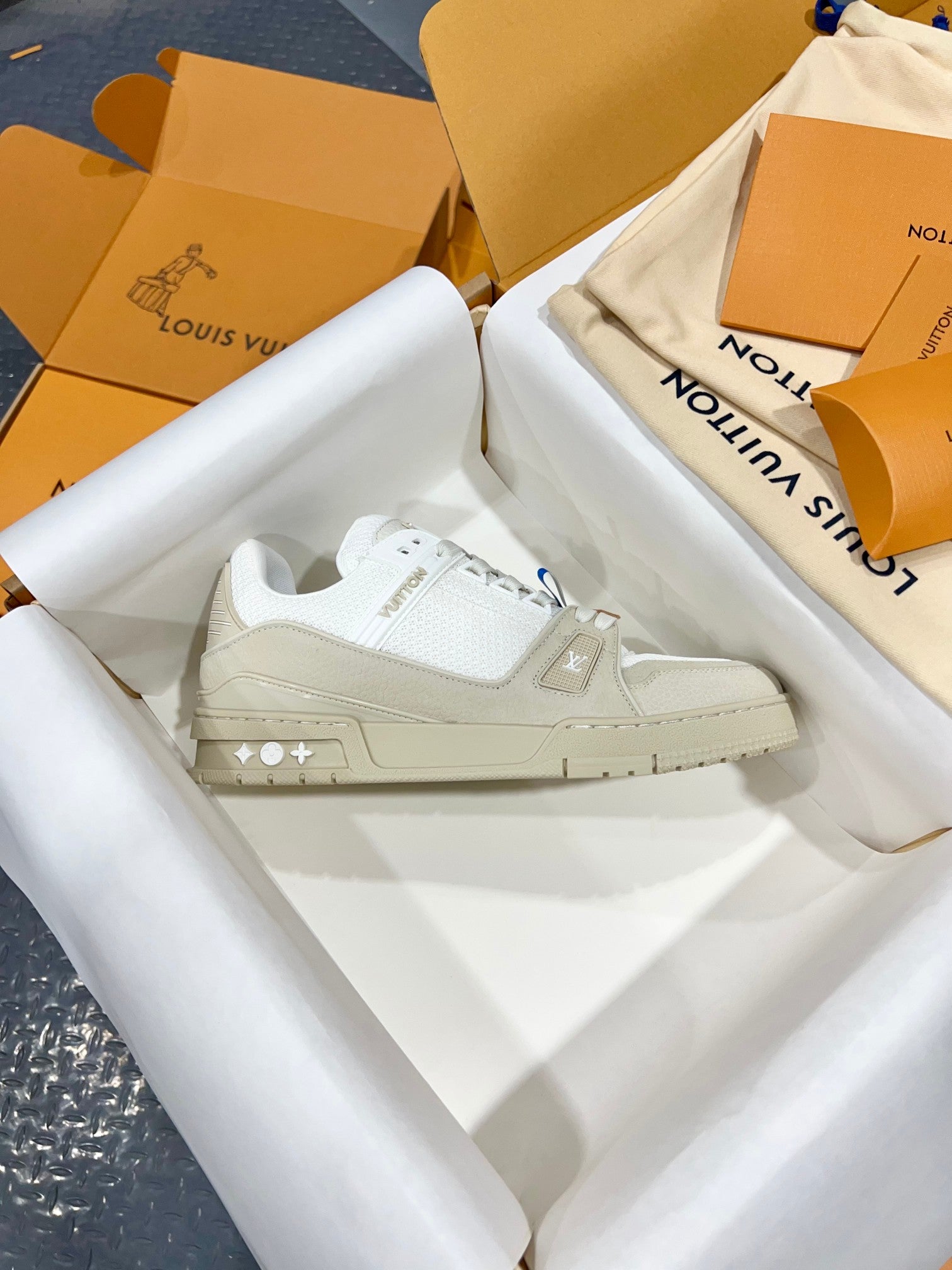 White Louis Vuitton trainer shoes with LV-printed side panels and lace-up front.
