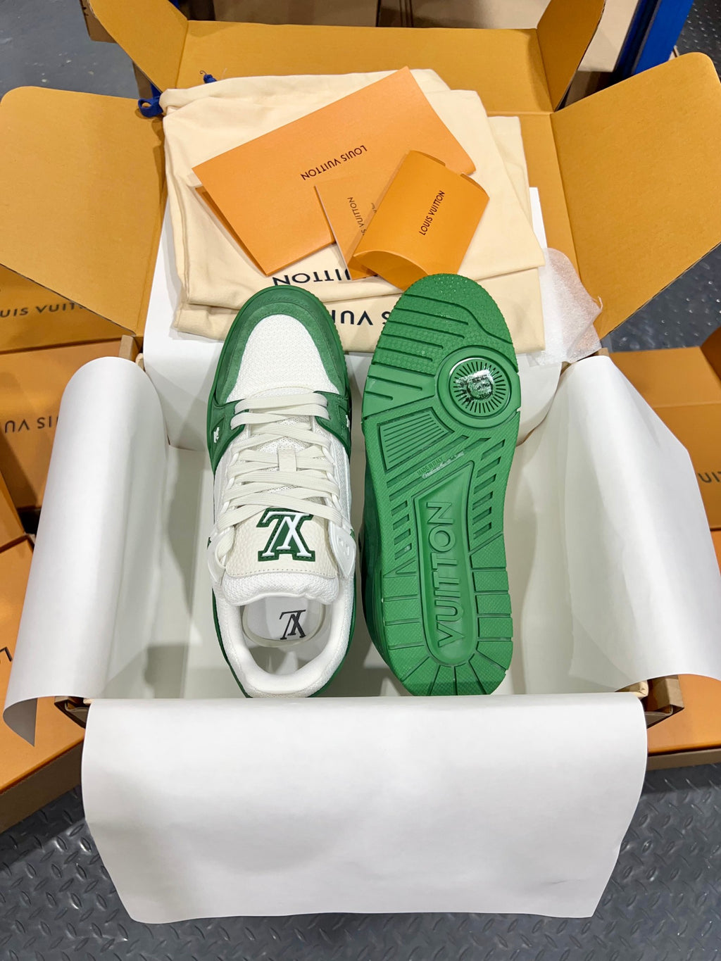 Green-and-white Louis Vuitton trainers showing soles with LV text and side print