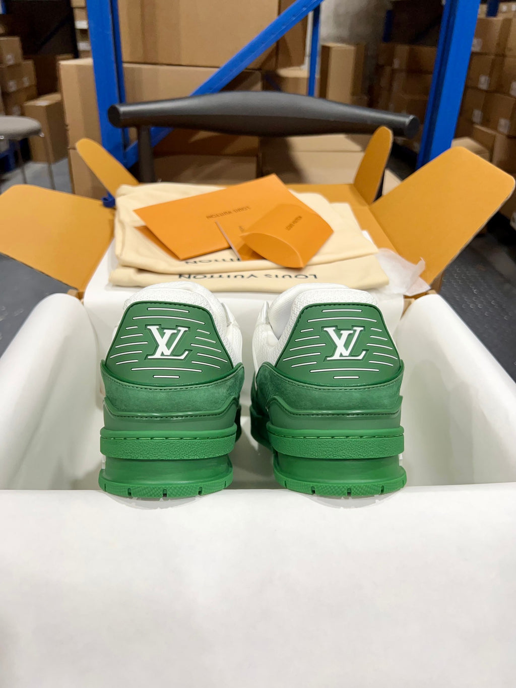 Green Louis Vuitton trainer pair viewed from back, stitched LV markings on heels