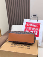 Coah monogram bag with tan trim shown on a display box