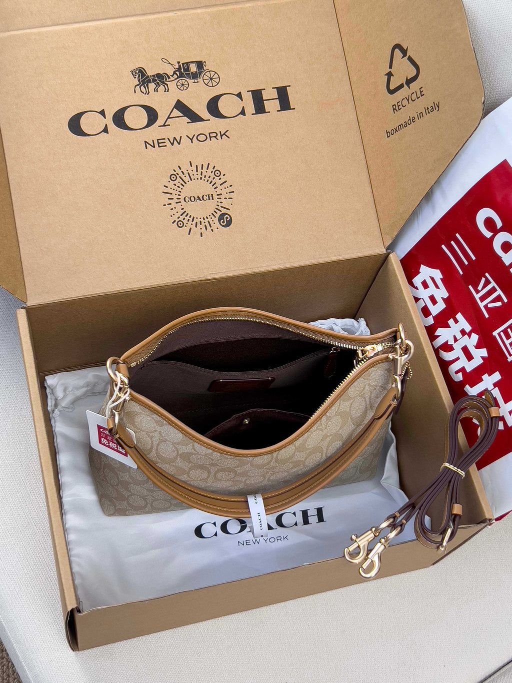 Coach signature hobo bag, light tan monogram, open top with gold-tone zipper and handles.