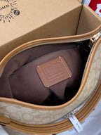 Coach signature hobo bag interior view, brown fabric lining and tan leather patch.