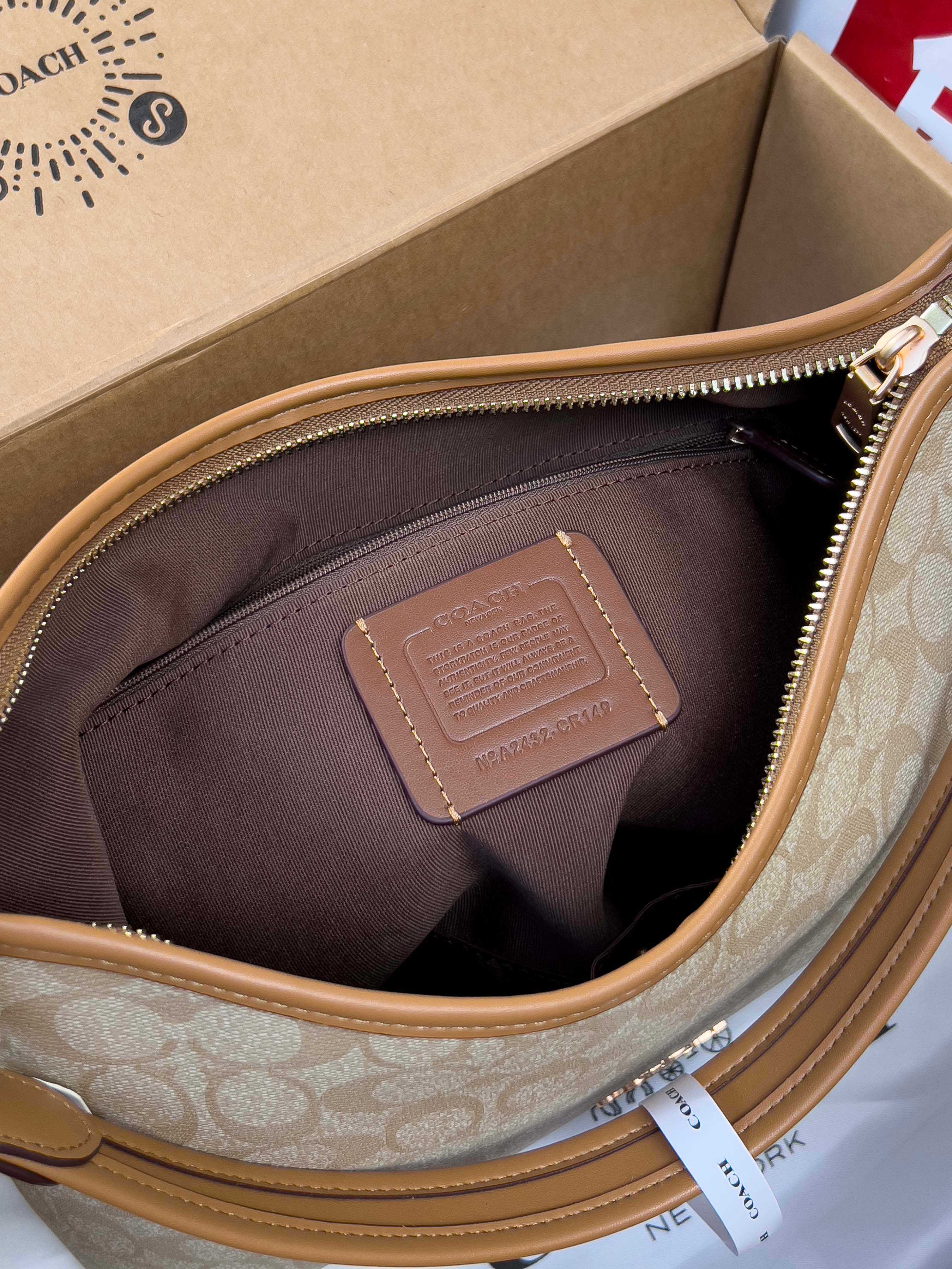 Coach signature hobo bag interior view, brown fabric lining and tan leather patch.