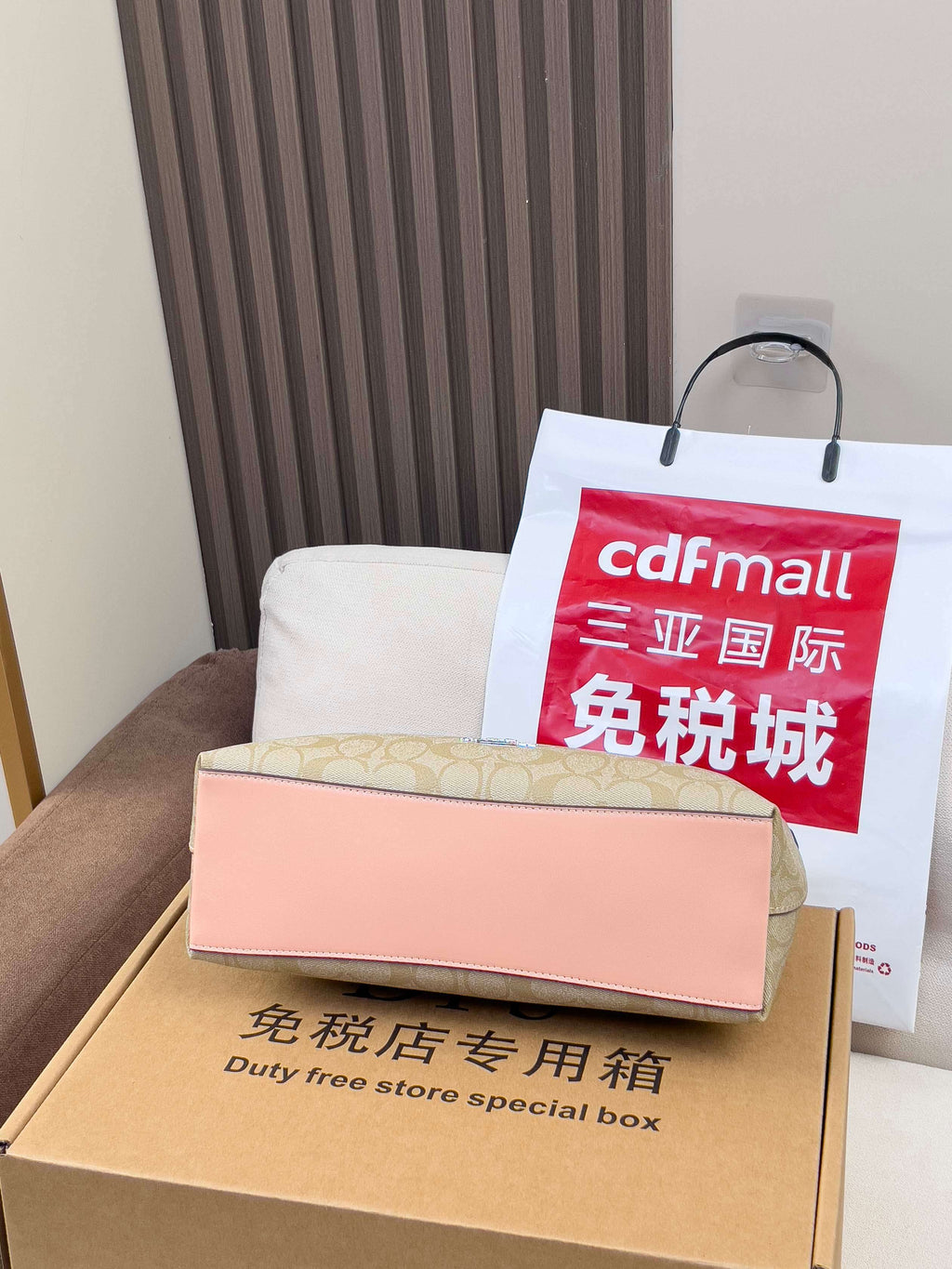 Duty free special box with label and a red shopping bag on a couch